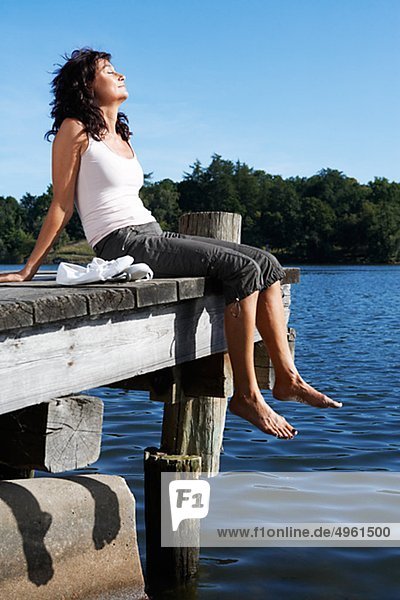 Eine Frau sitzt auf einer Mole an einem See  Schweden.