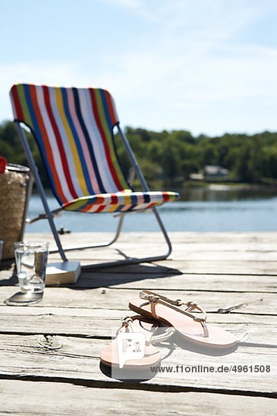 Ein Sun-Stuhl und Sandalen auf eine Mole  Schweden.