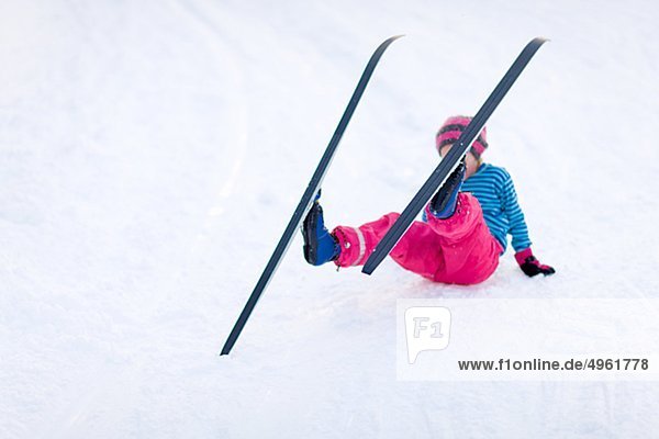 Junges Mädchen Ski- und runterzufallen