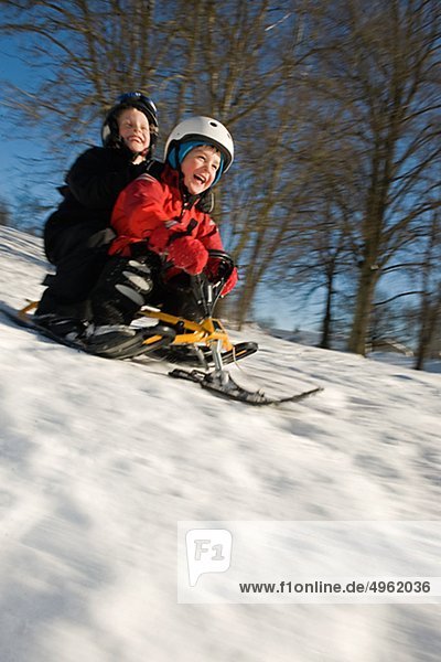 Boy and girl tobogganing on snow