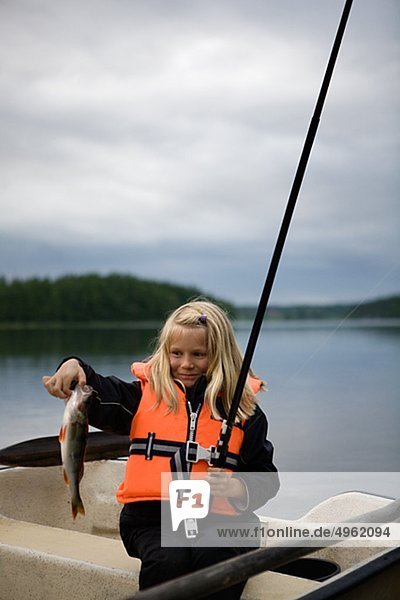 Girl holding fish and fishing rod