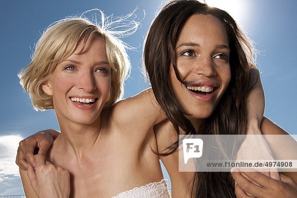 Zwei fröhliche junge Frauen unter blauem Himmel