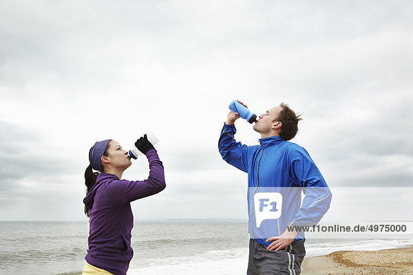 Couple drinking after exercise on beach