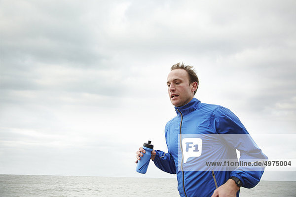Man running by the sea on cloudy day