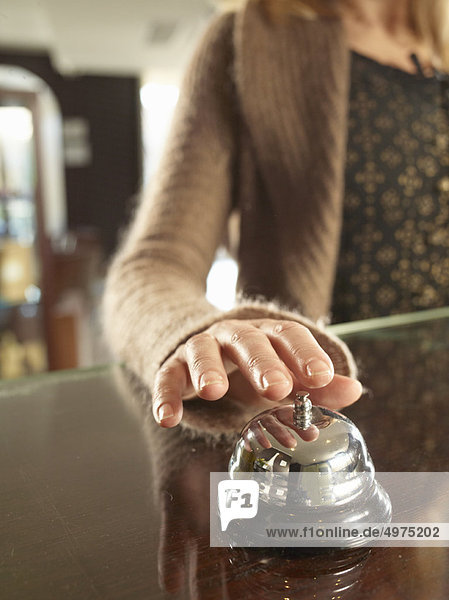 Close up of woman ringin a hotel porters bell