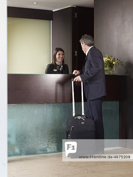 Senior man checking in at front desk of a hotel