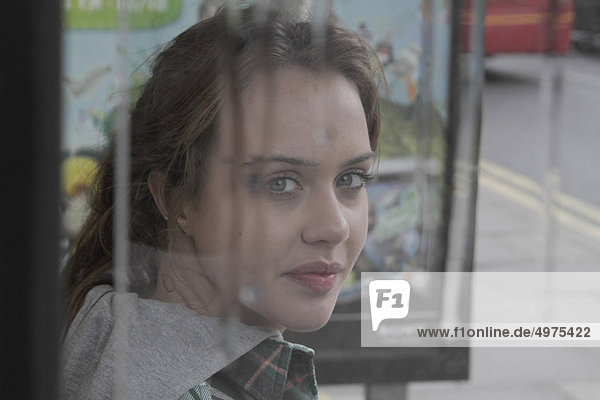 Young woman at bus shelter in rain