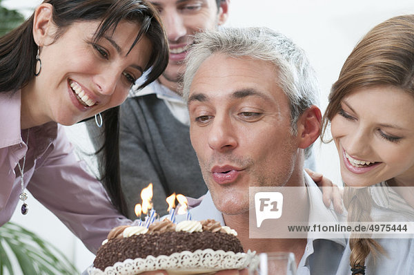 Freunde wehen auf Geburtstag Kerzen Kuchen