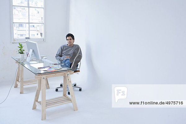 Mann am Computer sitzend mit erhobenen Füßen
