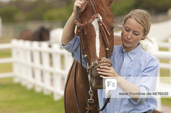 Woman putting reins on a horse