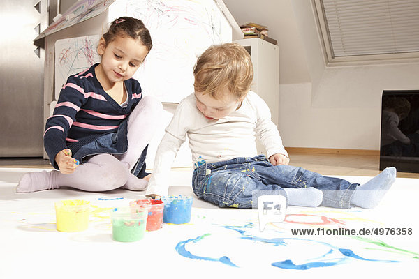 Girl and boy playing with finger paint