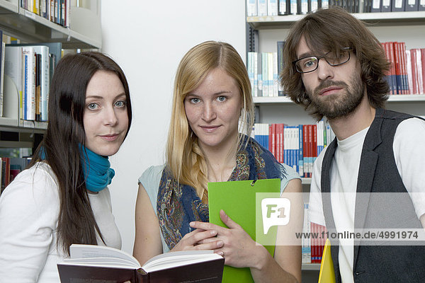 Three students in library  Darmstadt  Hesse  Germany