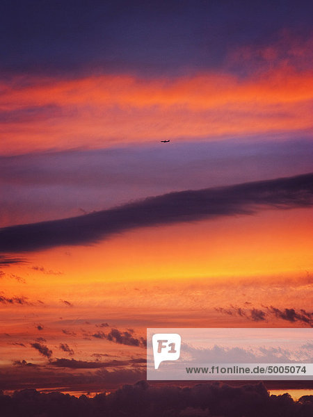 Ein Flugzeug fliegt in den Himmel  wenn die Sonne untergeht.
