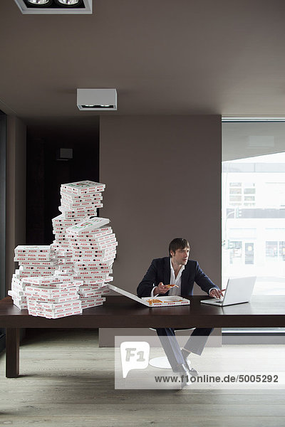 Many pizzas for businessman at home on laptop.