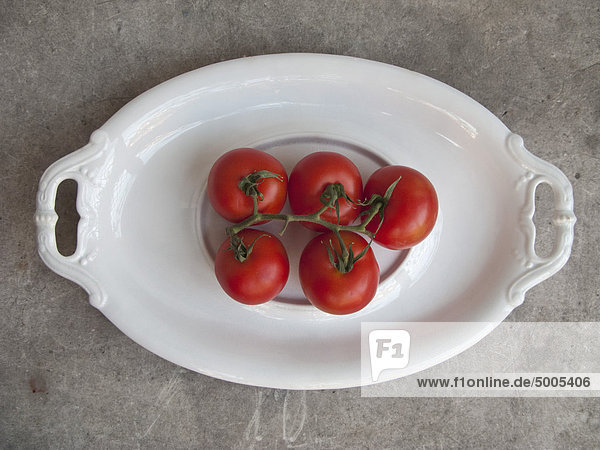 Fünf Tomaten auf dem Teller.
