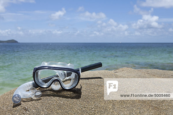 A diving mask and snorkel on a rock near the sea