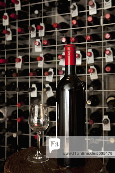 A bottle of wine and a wineglass in a cellar