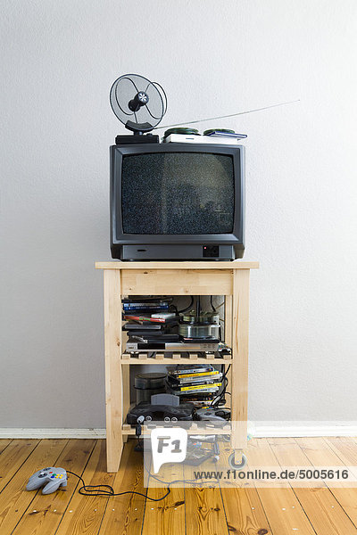 Ein Fernseher auf einem Schrank mit vielen DVDs und Videospielen