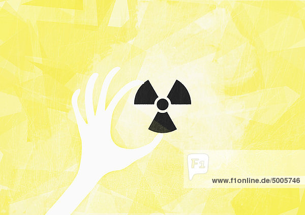 Eine Hand  die ein radioaktives Symbol hält.