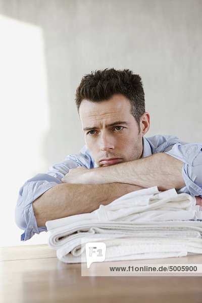 Ein müder Mann ruht auf einem Stapel gefalteter Wäsche.