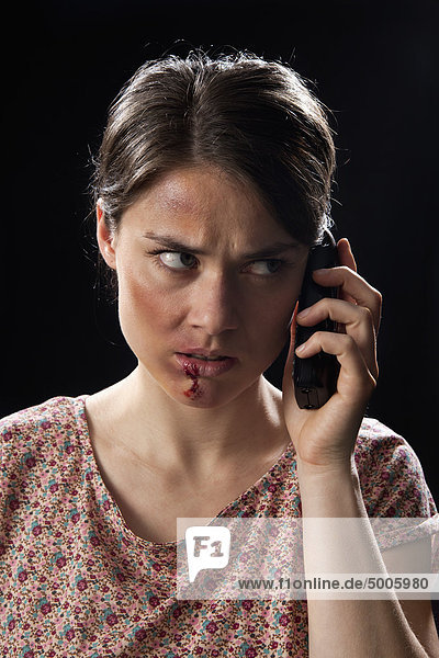 A beaten up woman using a cordless phone