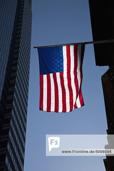 Die amerikanische Flagge zwischen zwei hohen Gebäuden mit klarem  blauem Himmel.