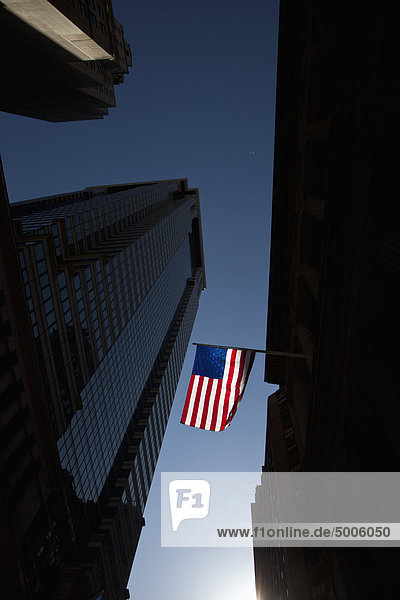 Die amerikanische Flagge zwischen den Wolkenkratzern mit dem Hintergrund eines klaren blauen Himmels