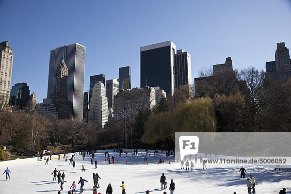 Viele Menschen Eislaufen mit hohen New Yorker Gebäuden im Hintergrund