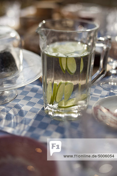 Wasserkrug mit Limettenscheiben auf dem Esstisch im Freien