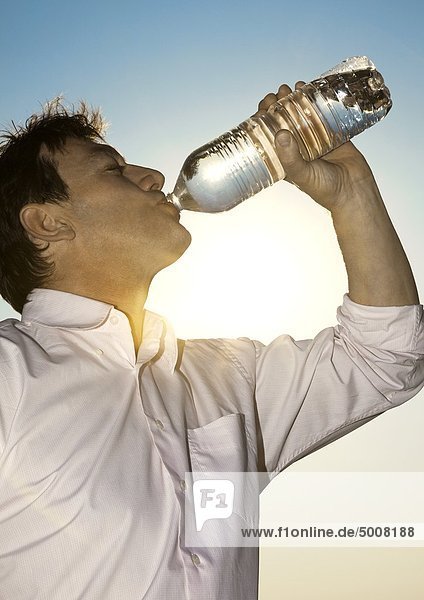 Mann im Freien trinkt aus einer Wasserflasche