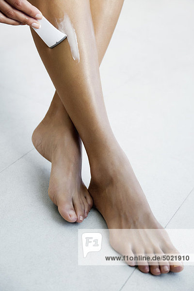 Woman applying hair removal cream to leg