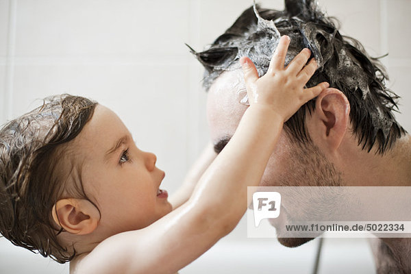 Kleinkind Junge wäscht Vaters Haare im Bad