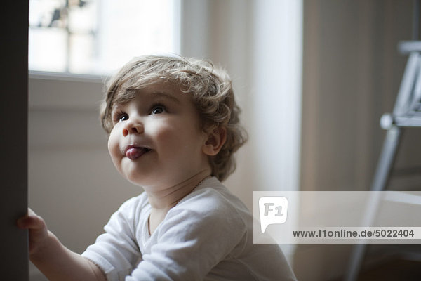 Kleinkind Junge  Zunge herausstreckend  nach oben schauend  Portrait