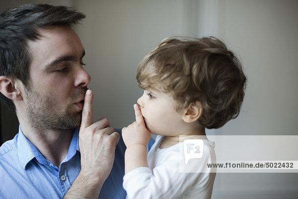 Father teaching toddler son to hush