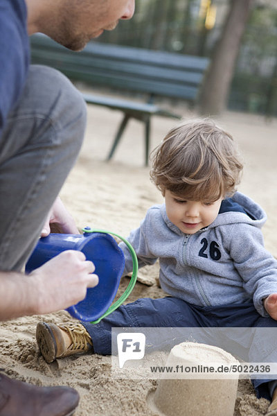 Kleinkind Junge spielt mit seinem Vater im Sand