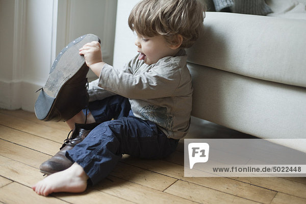 Toddler boy playing with parent's shoes