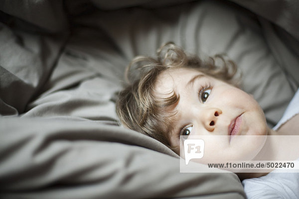 Toddler boy lying in bed  portrait