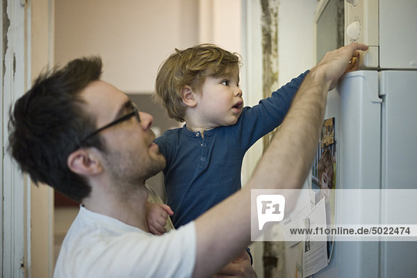 Toddler boy helping father using microwave