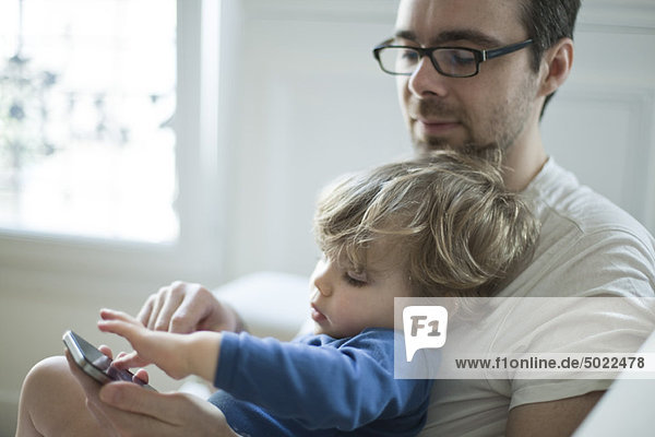 Toddler boy touching father's cell phone curiously