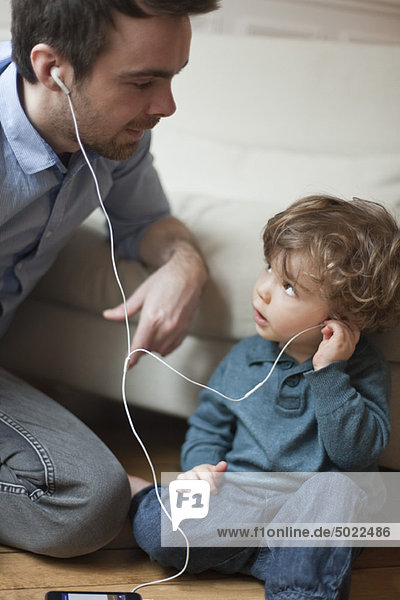 Vater und Kleinkind Sohn hören MP3-Player mit Kopfhörer  Portrait