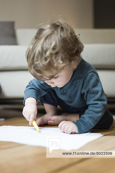 Toddler boy drawing on paper