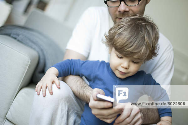 Kleinkind Junge beobachtet Vater mit dem Handy
