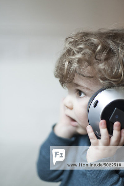 Toddler boy listening to music with headphones  portrait