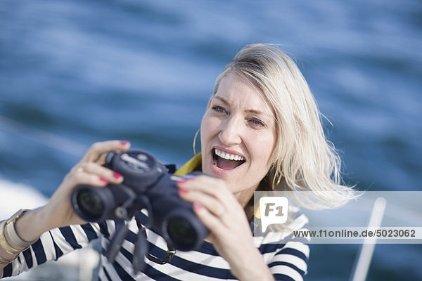 Woman using binoculars on boat