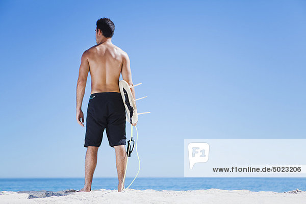 Mann mit Surfbrett am Strand