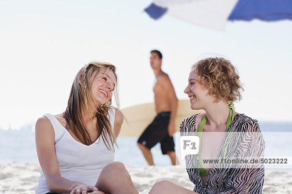Smiling women talking on beach