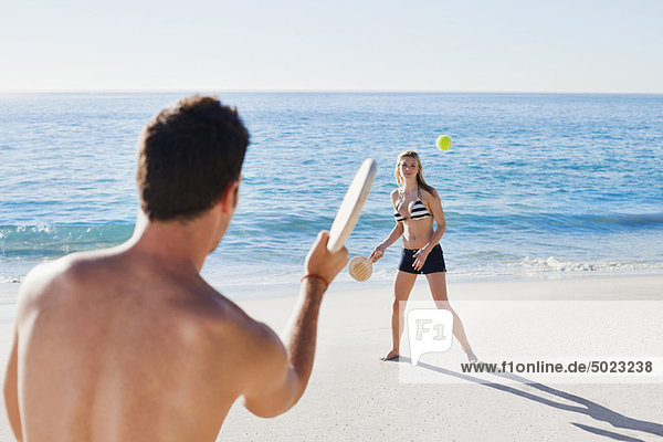 Couple playing tennis on beach