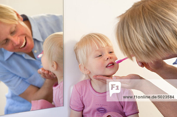 Father brushing toddler daughter’s teeth
