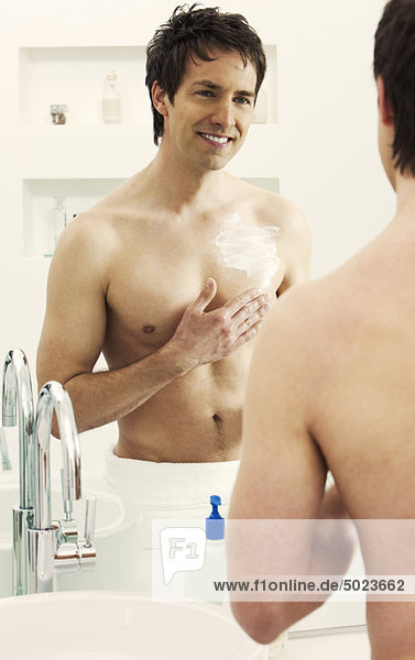Man moisturizing chest in bathroom