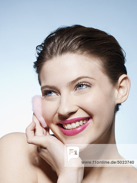 Smiling woman cleansing her face